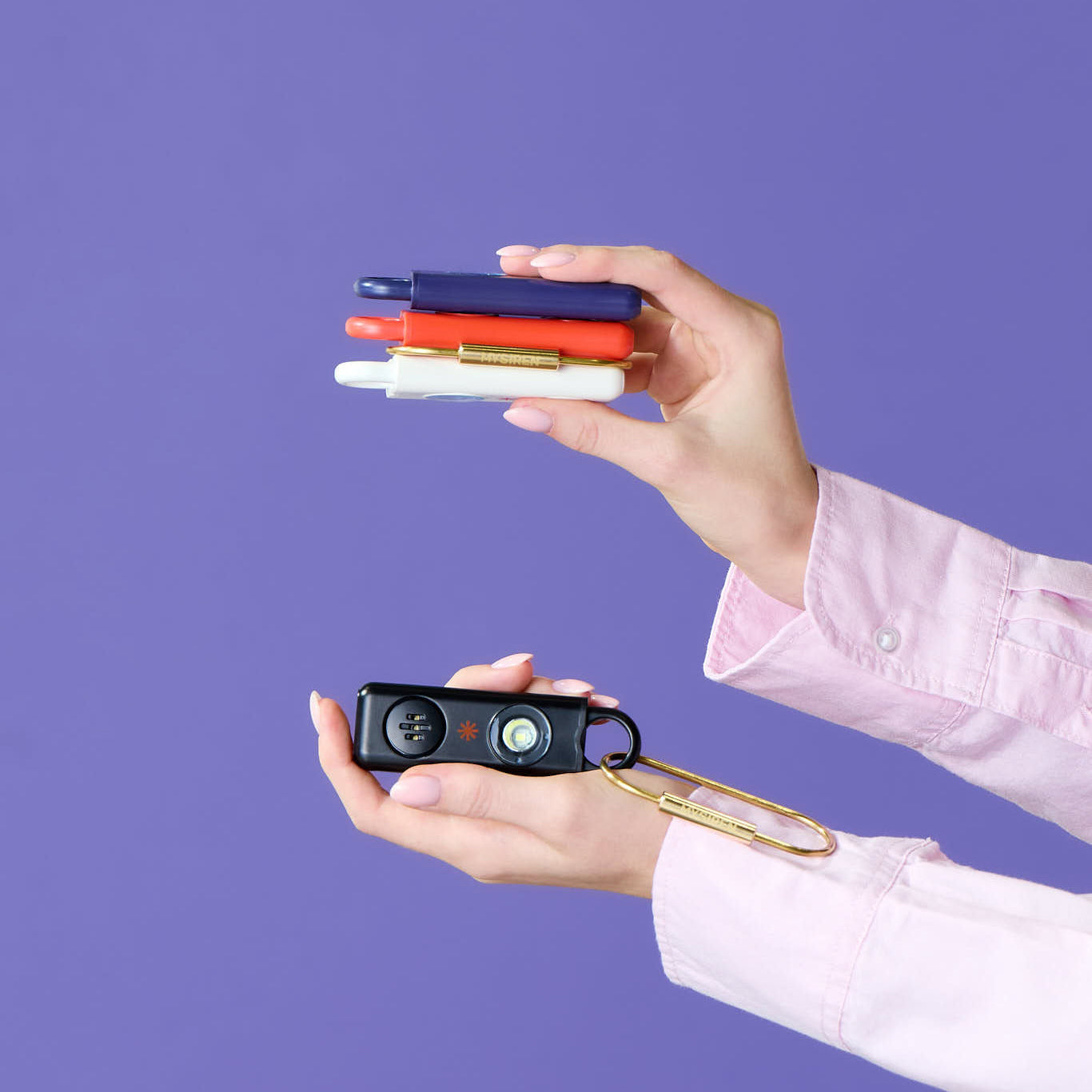 " person holding small black personal alarm with My Siren gold caribe keychain"